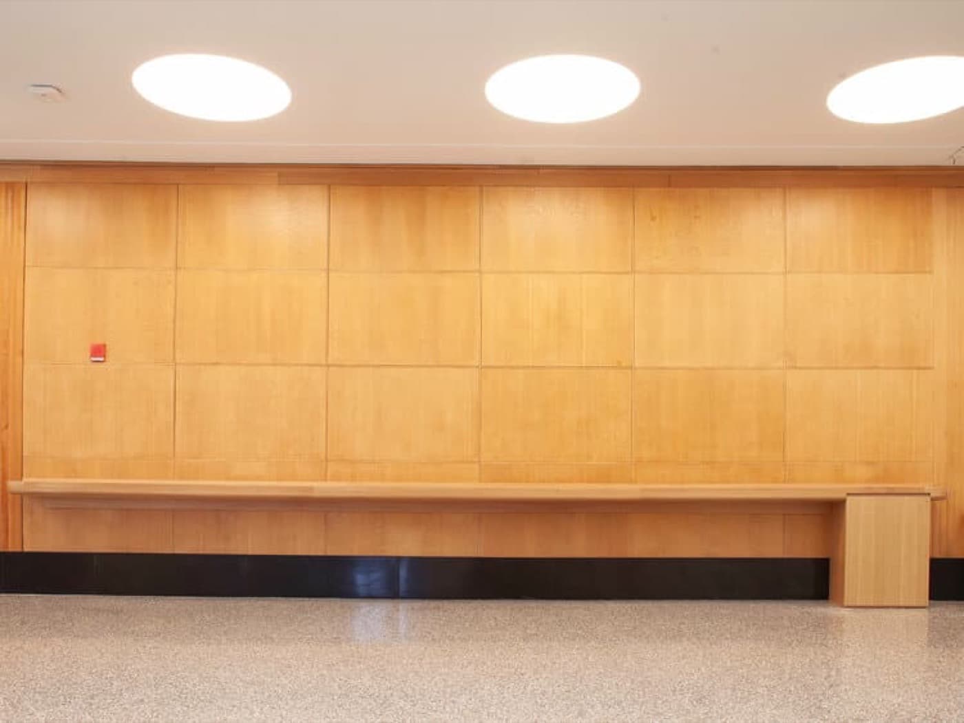 Commercial hallway featuring light timber wall panelling and an integrated built-in bench