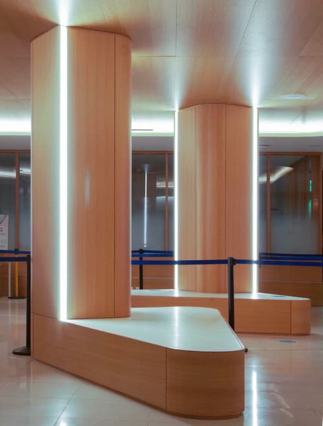 Commercial lobby featuring timber-clad columns with integrated vertical light strips and built-in benches