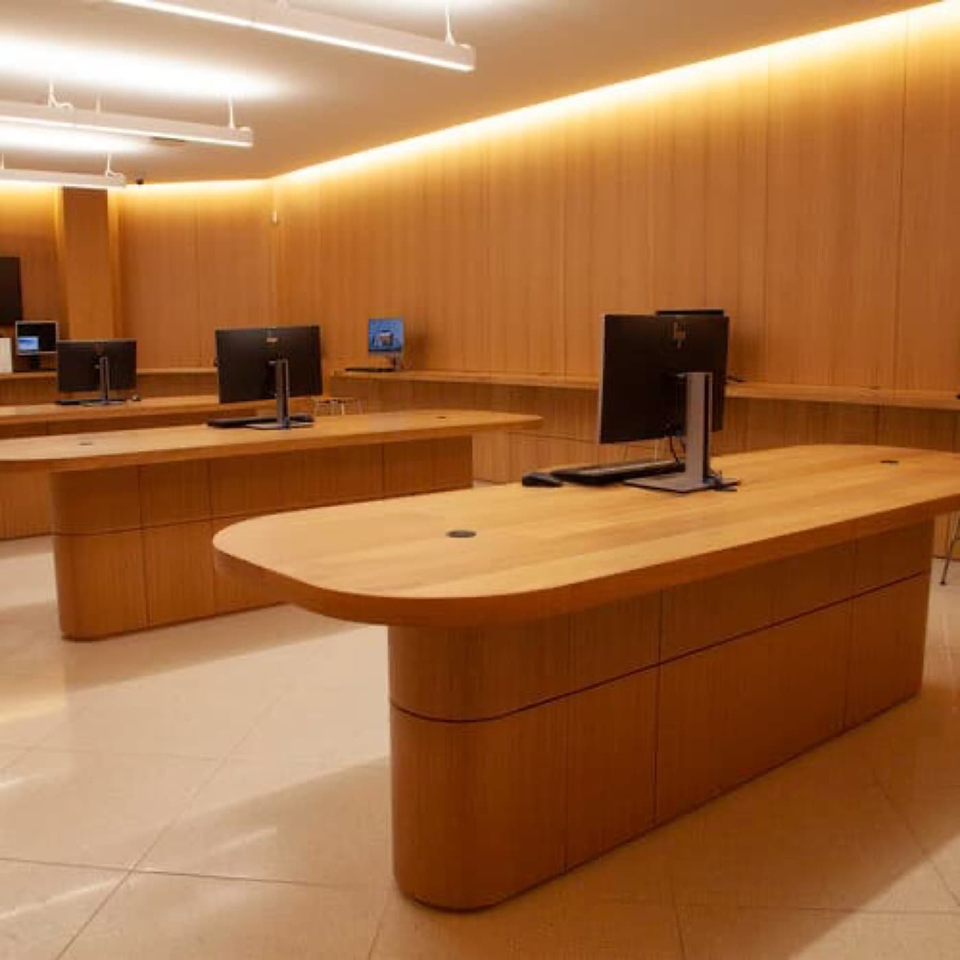 Commercial office workspace with custom light wood island desks and matching full-height wall panelling