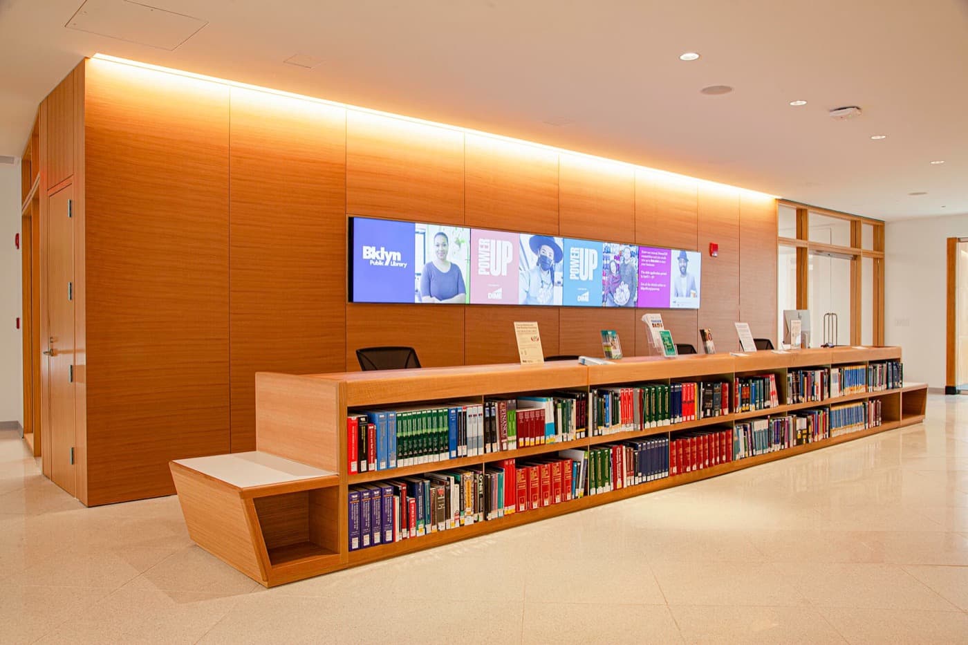 Library lobby featuring warm timber wall panelling and a custom reception desk with integrated bookshelves
