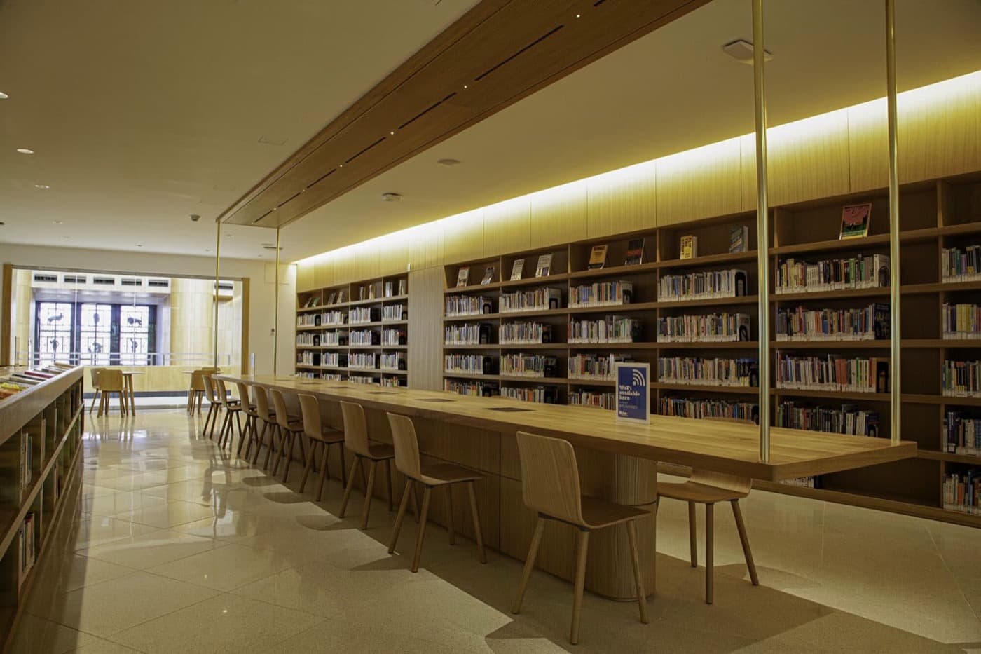 Library with built-in timber shelving and a long suspended wood study table
