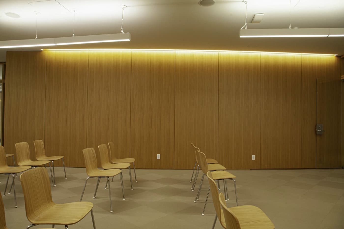 Conference room featuring full-height oak-toned timber wall panelling with integrated cove lighting