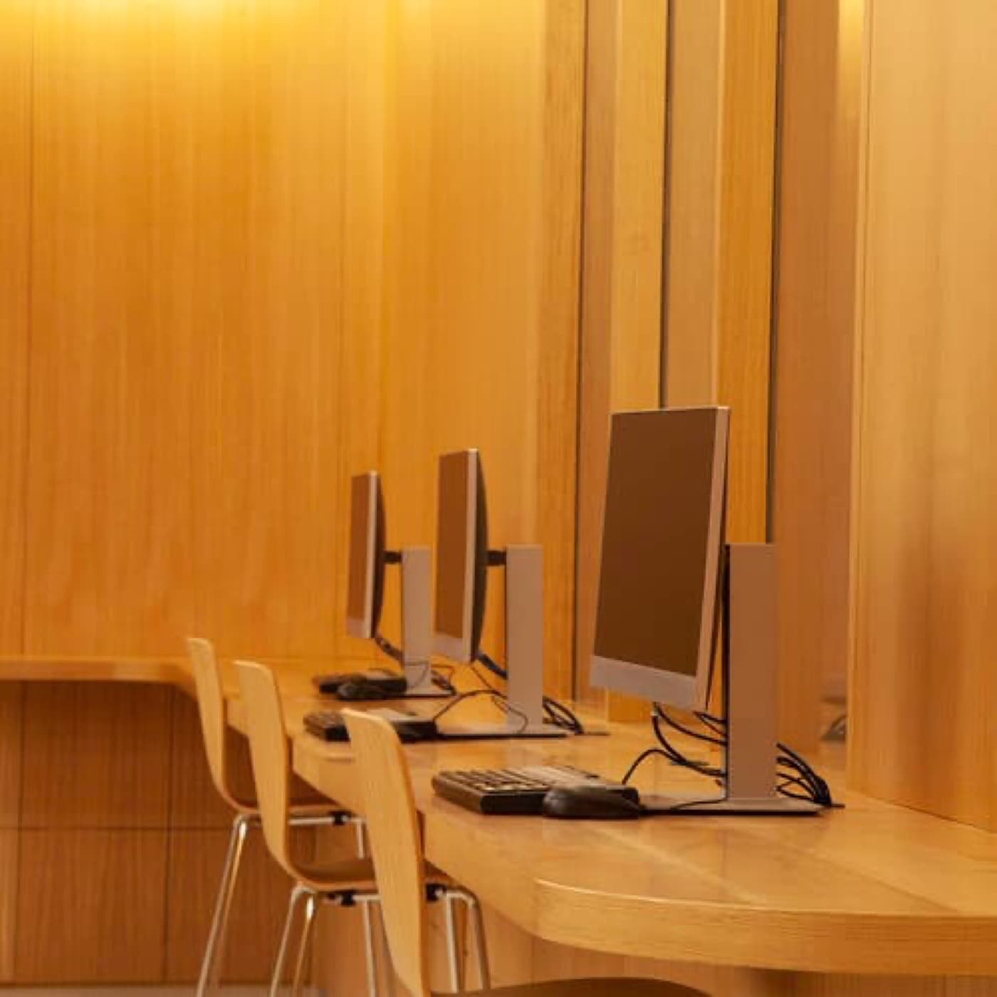Office workspace featuring a built-in curved timber desk and warm timber wall panelling