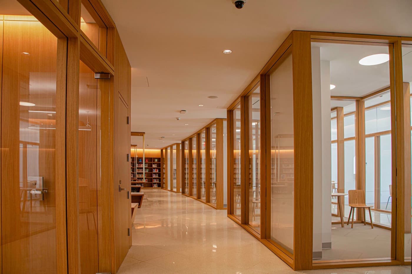Office hallway featuring custom timber-framed glass partition walls and polished tile flooring
