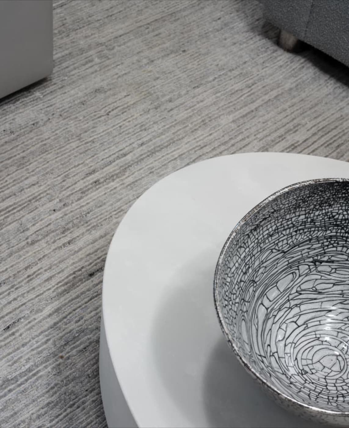 Living room detail with a round white coffee table over a textured grey rug