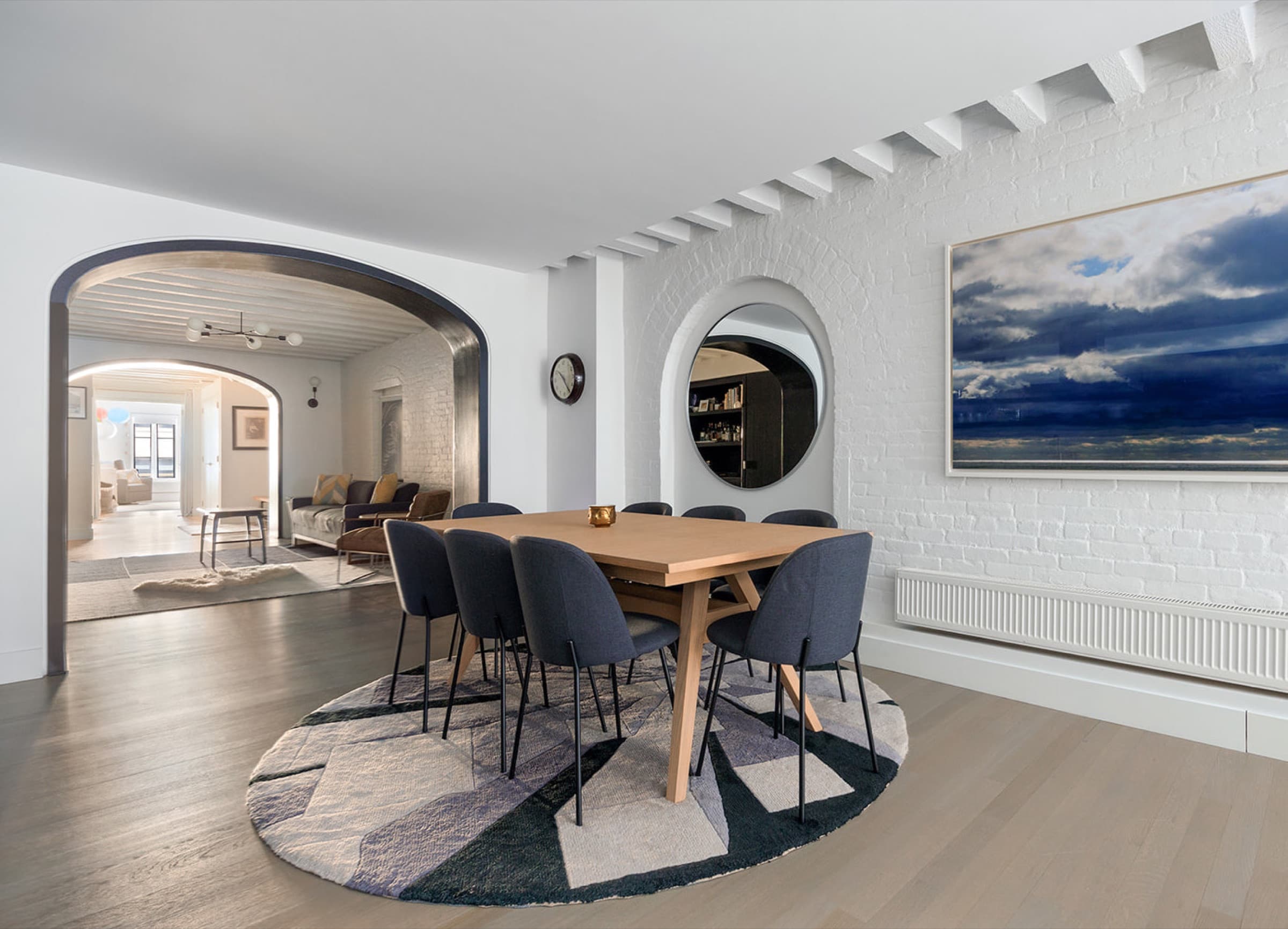 Dining room with dark metal lined archway, painted brick wall, and exposed ceiling joists
