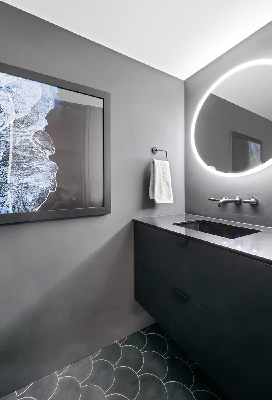 Modern powder room with floating dark vanity, backlit mirror, and scalloped floor tile