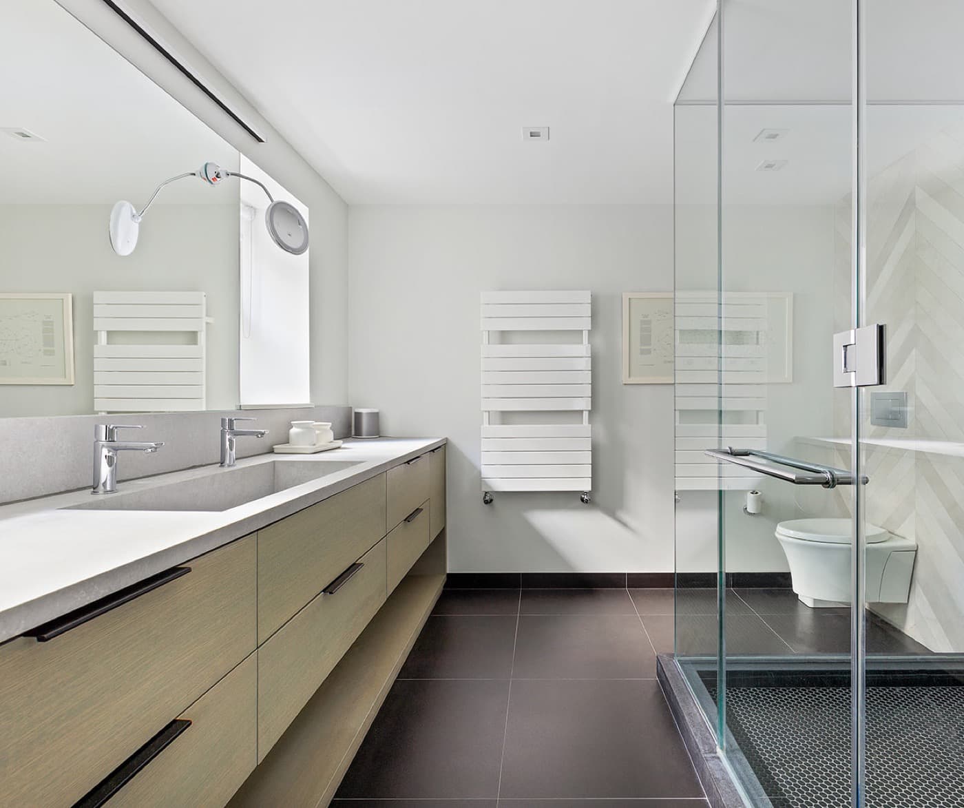 Bathroom with long light-toned timber vanity, stone double sink, and glass shower enclosure