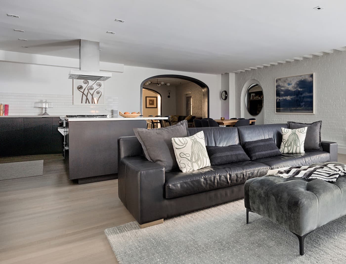 Open-plan living room and kitchen featuring dark cabinetry, central island, and arched plaster openings