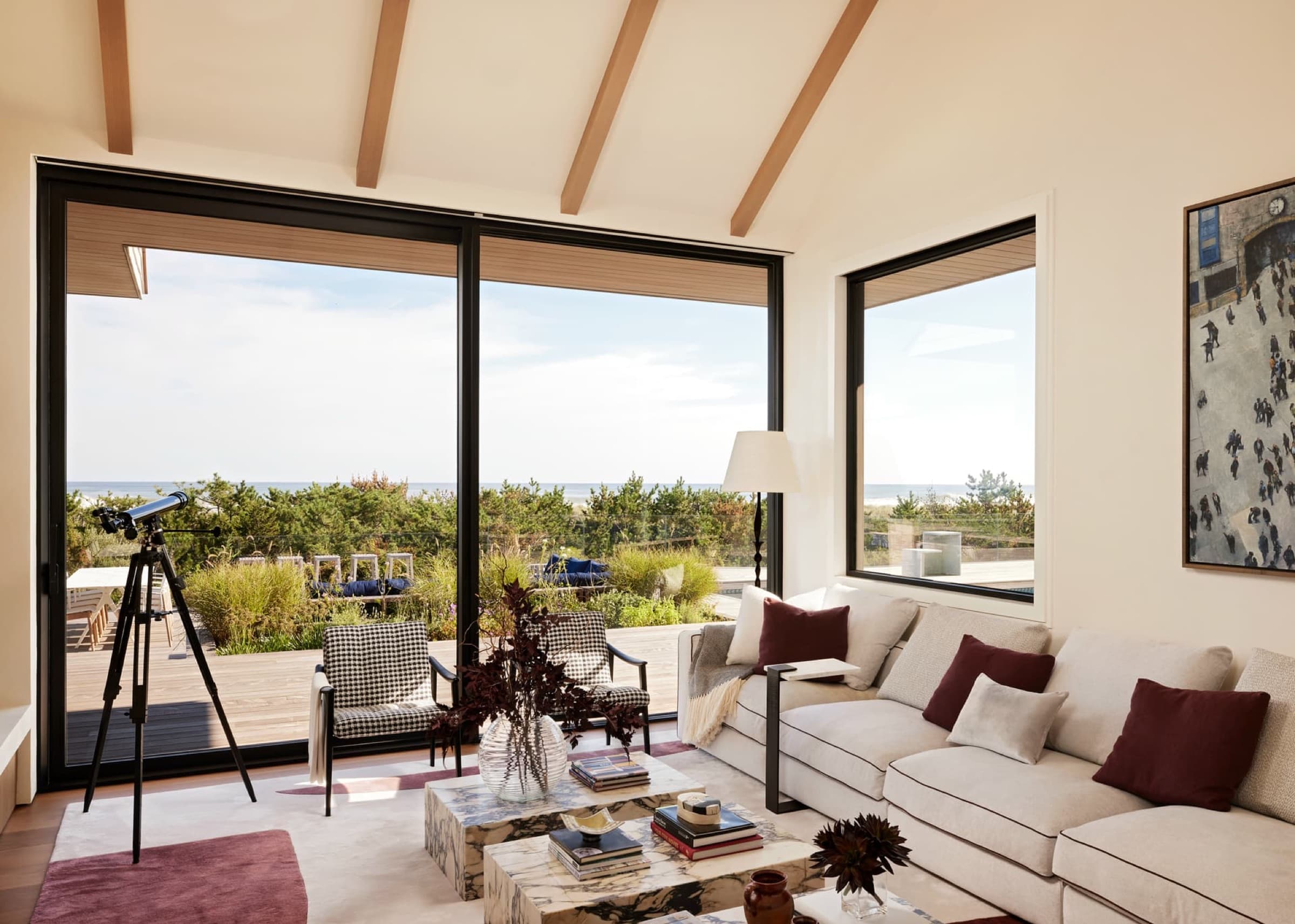 Living room with timber ceiling beams and expansive dark-framed sliding glass doors