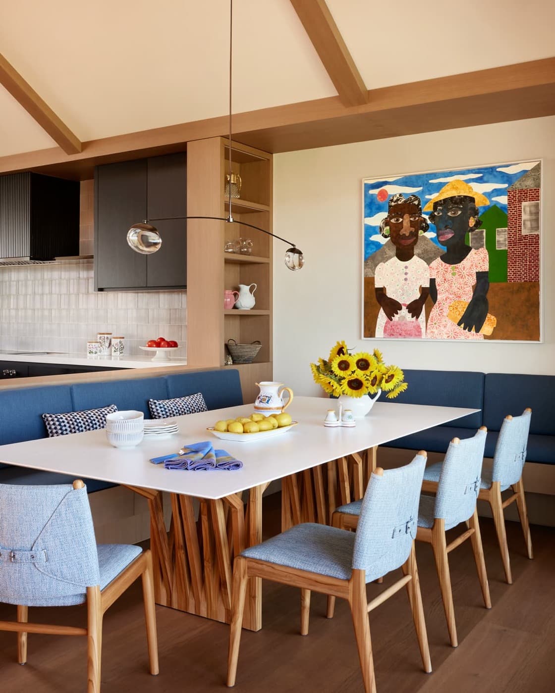 Dining area featuring built-in blue banquette seating, oak-toned timber shelving, and exposed ceiling beams