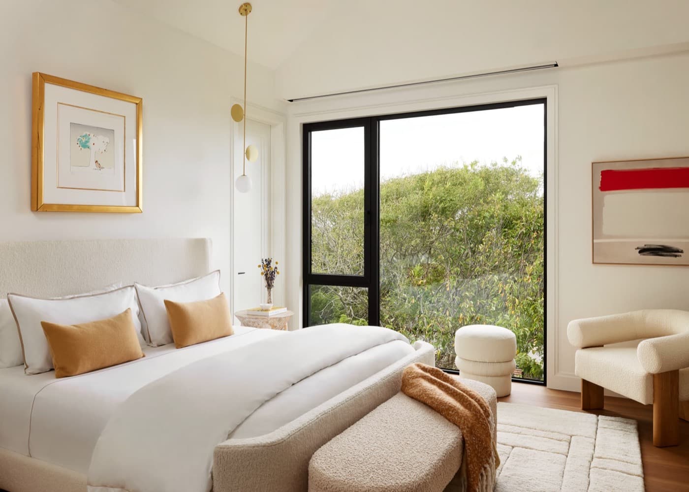Bedroom featuring large dark metal framed window overlooking greenery and upholstered bed