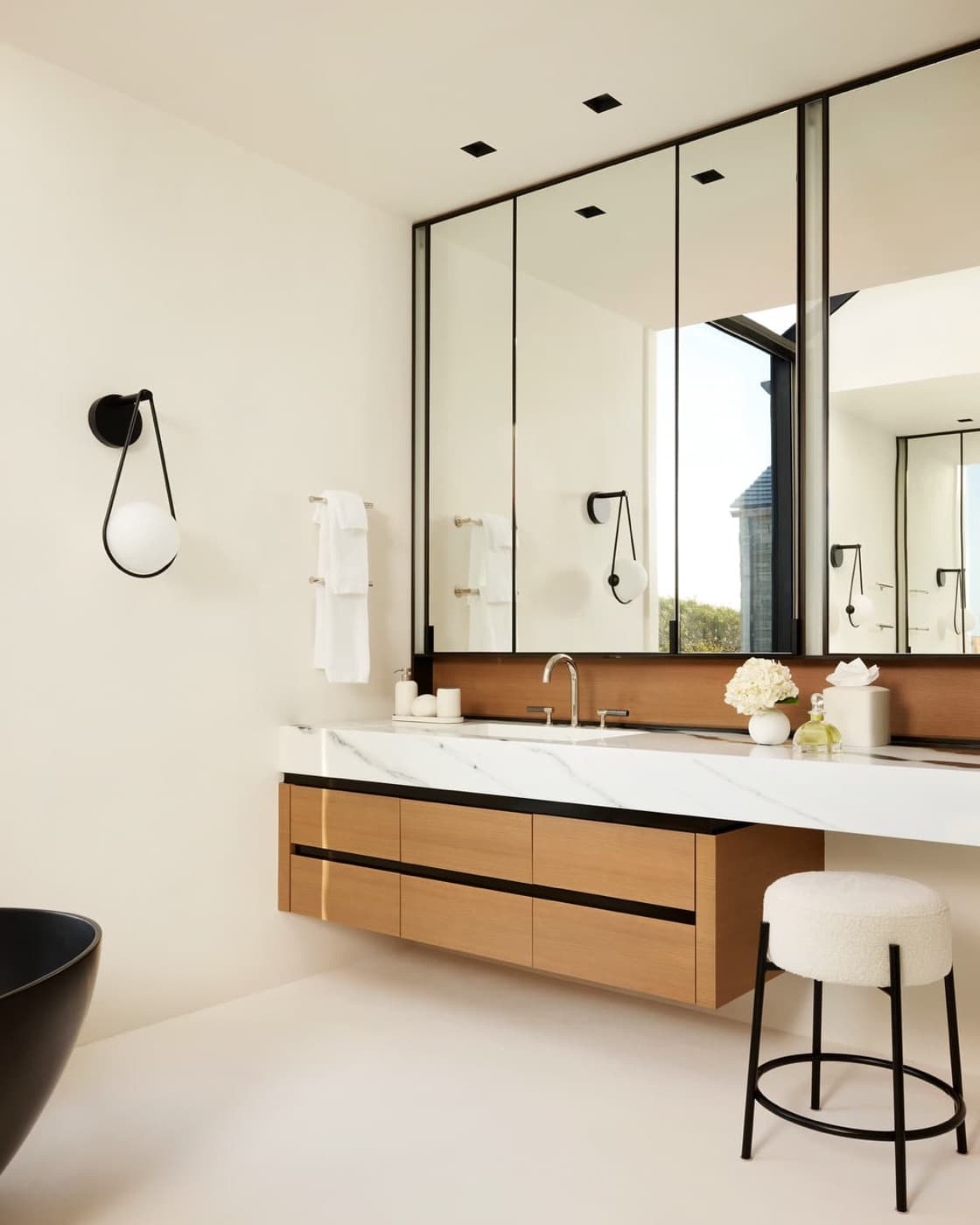 Bathroom with floating timber vanity, thick pale veined stone countertop, and large mirrored medicine cabinets