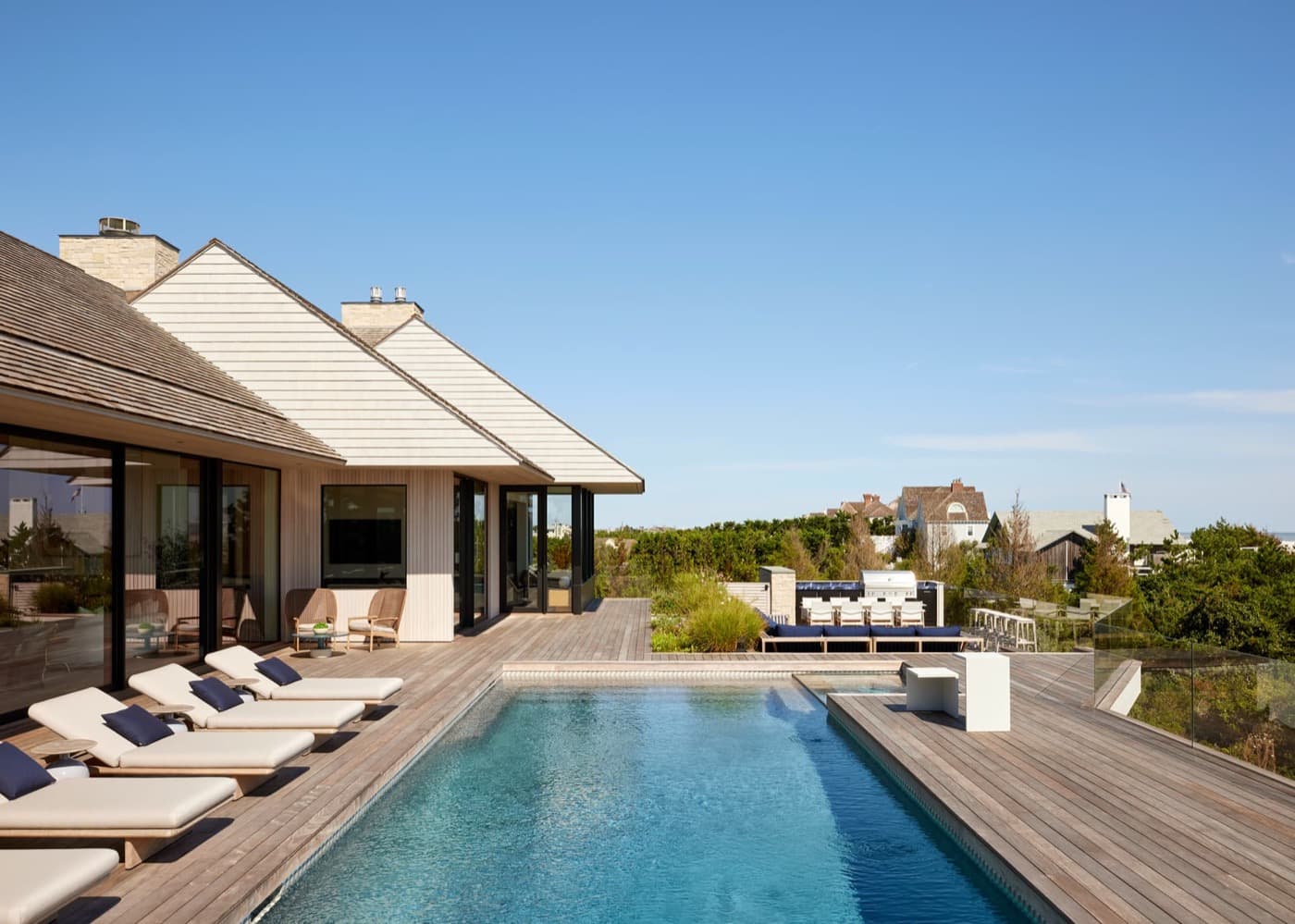 Outdoor terrace with timber plank decking, rectangular swimming pool, and contemporary shingle-clad house exterior