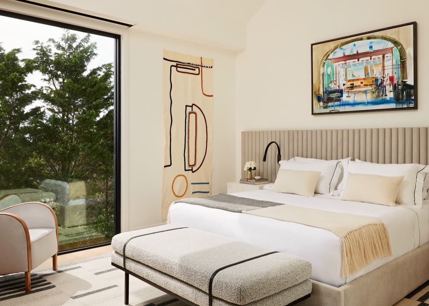 Bedroom featuring a fluted upholstered headboard panel and full-height window to garden views