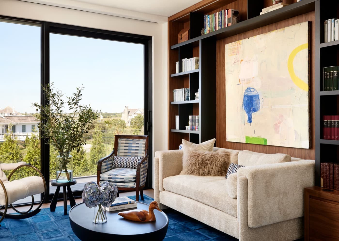 Living room with built-in dark shelving and timber wall panelling beside large sliding doors