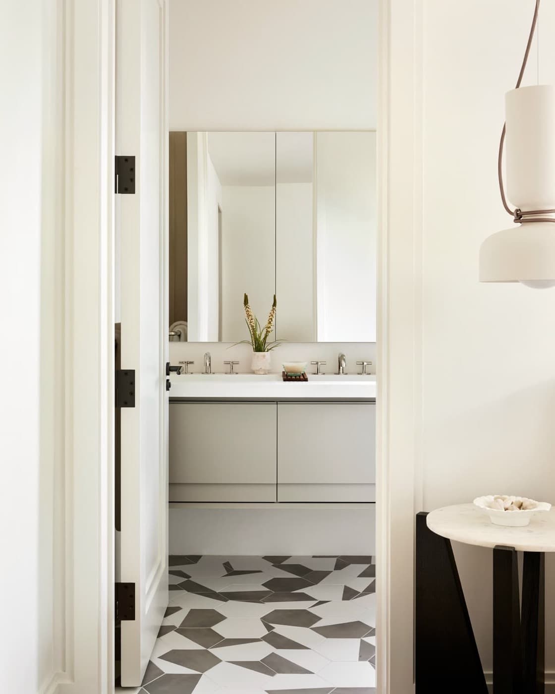 Bathroom doorway view of a floating vanity, mirrored cabinets, and patterned geometric floor tiles