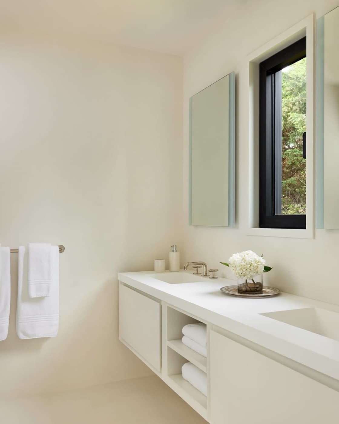 Bathroom with a floating white custom vanity, integrated sinks, open shelving, and rectangular mirrors
