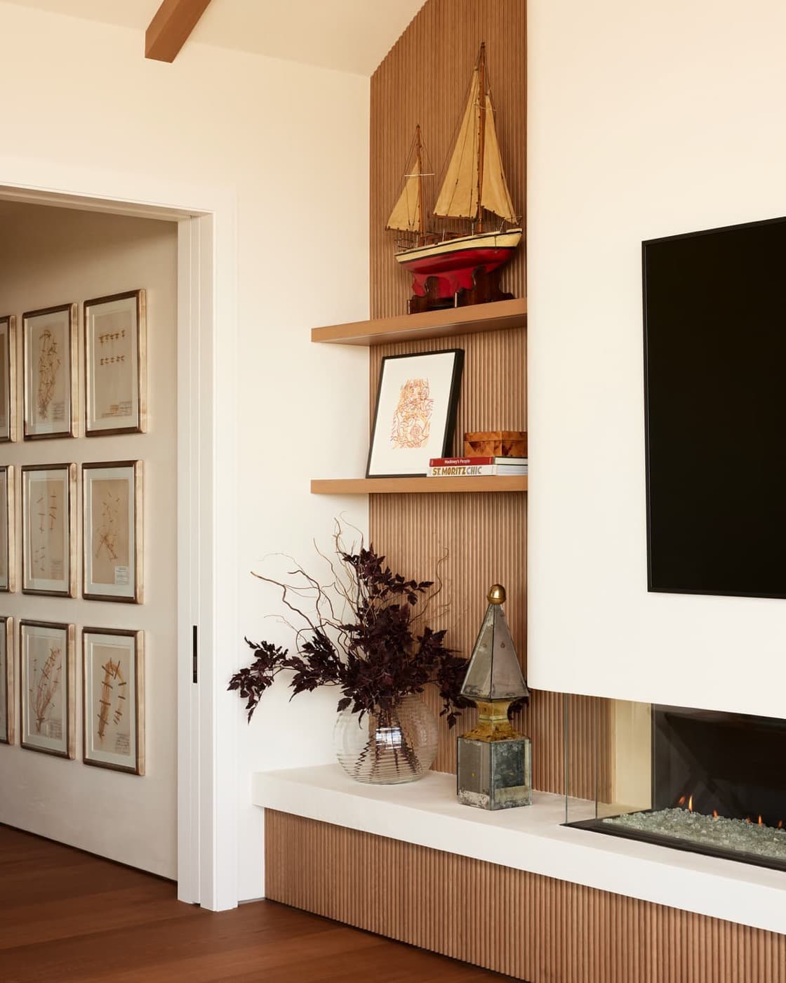 Living room fireplace wall with fluted timber panelling, floating display shelves, and low stone hearth