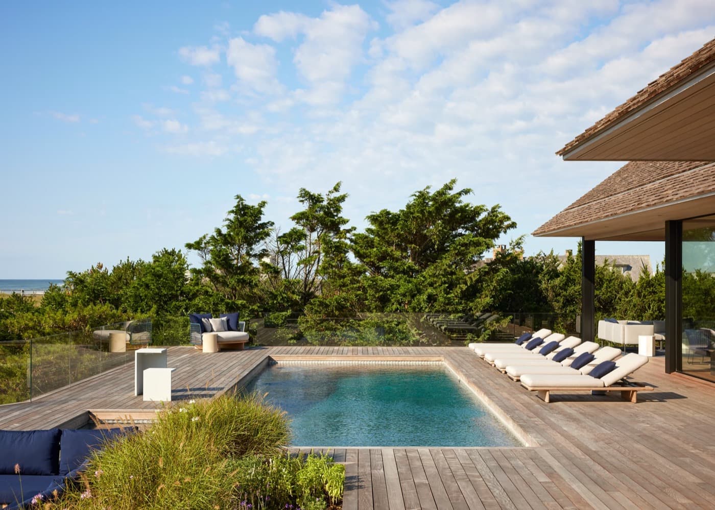 Outdoor pool deck featuring timber planking, an in-ground swimming pool, and glass railing