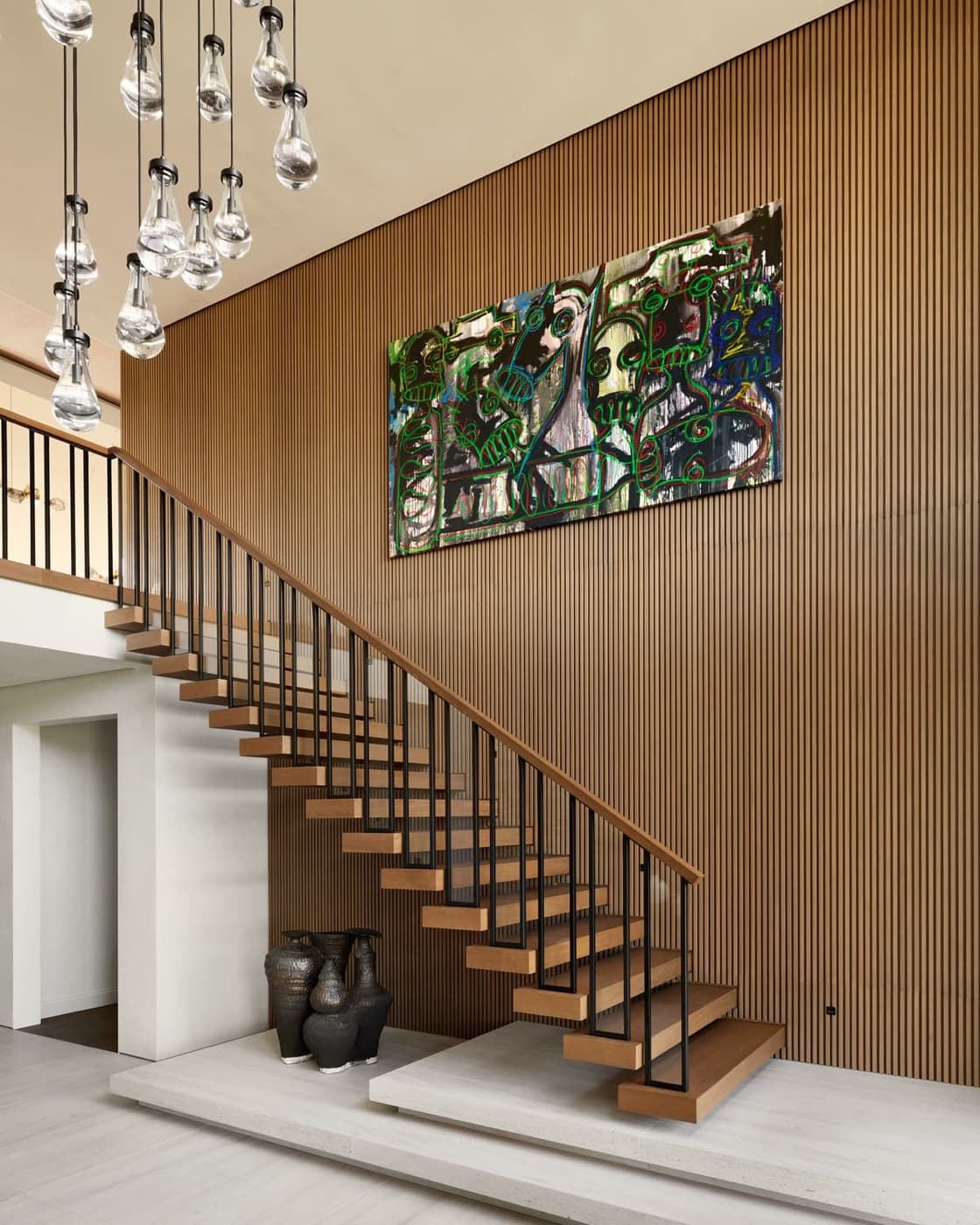 Double-height entryway with floating timber staircase and floor-to-ceiling slatted timber wall paneling