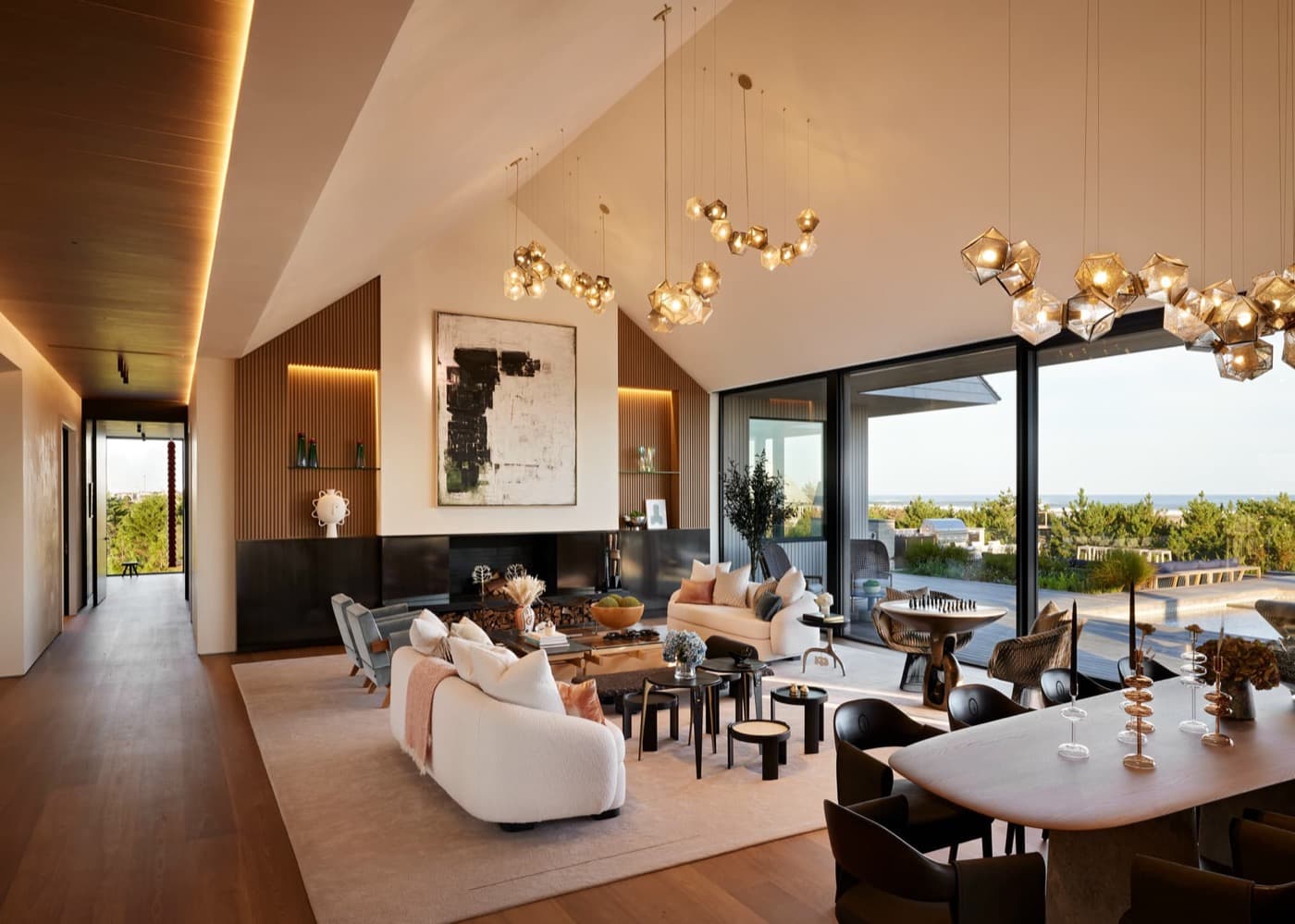 Vaulted open-plan living room with slatted timber panelling, fireplace cabinetry, and expansive glass doors