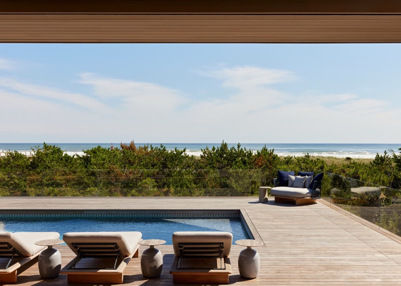 Outdoor pool deck featuring weathered timber decking, swimming pool and glass railing overlooking the ocean