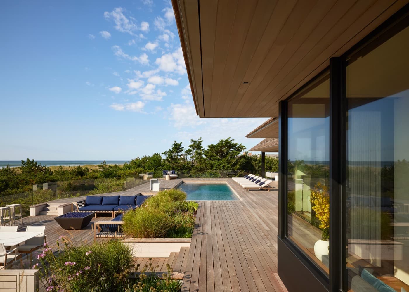 Outdoor timber deck and swimming pool with sunken seating beneath a wood-clad soffit
