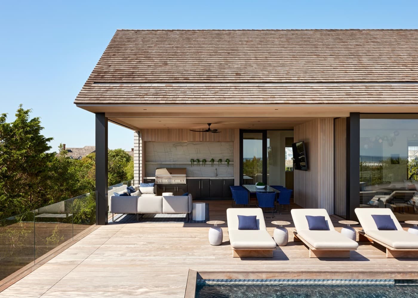Covered outdoor patio and pool deck with built-in kitchen cabinetry and vertical timber cladding