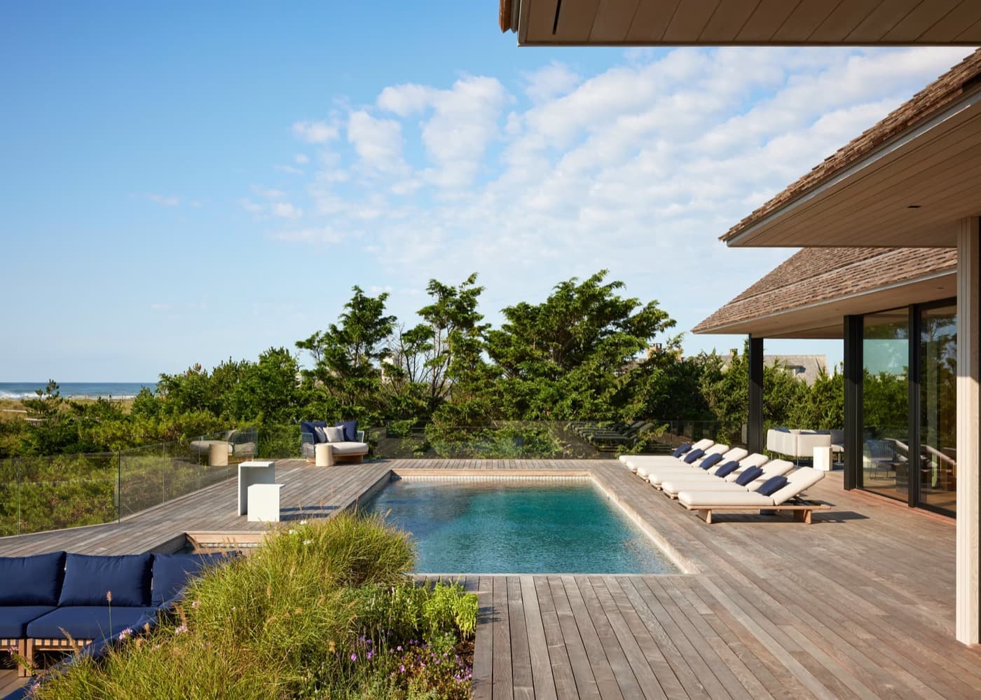 Oceanfront terrace with weathered timber decking, in-ground swimming pool, and wood-clad roof overhang