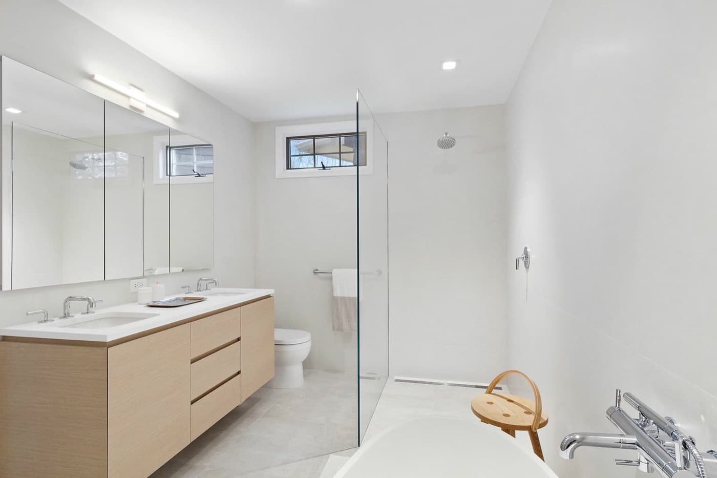 Bathroom featuring a light-toned timber floating vanity, mirrored cabinets, and glass shower