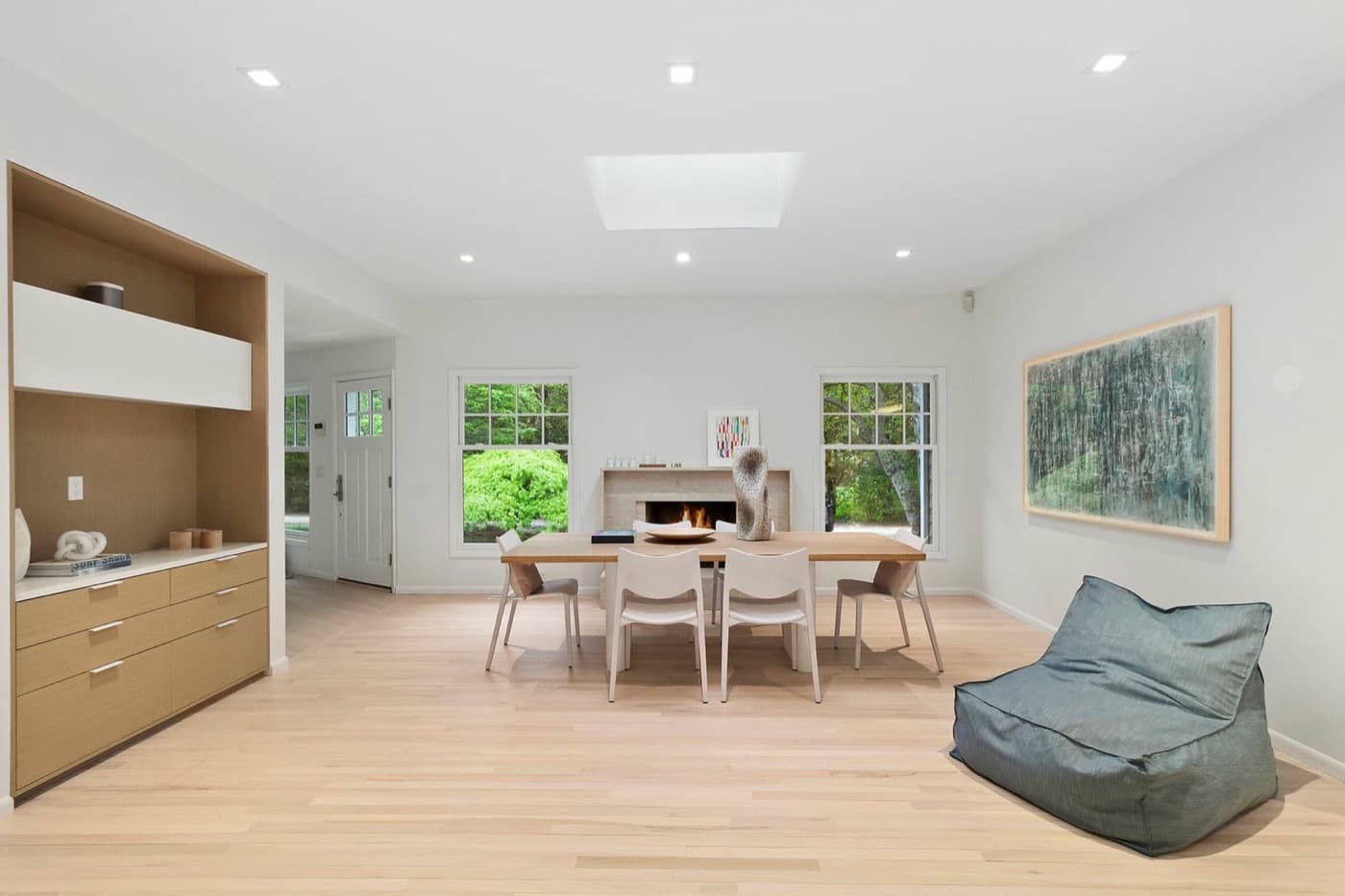 Open dining room with custom light timber built-in cabinetry and stone fireplace
