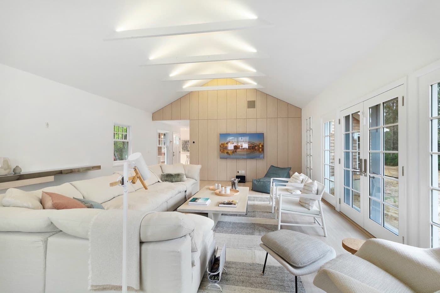 Vaulted living room with pale timber wall panelling and illuminated ceiling beams