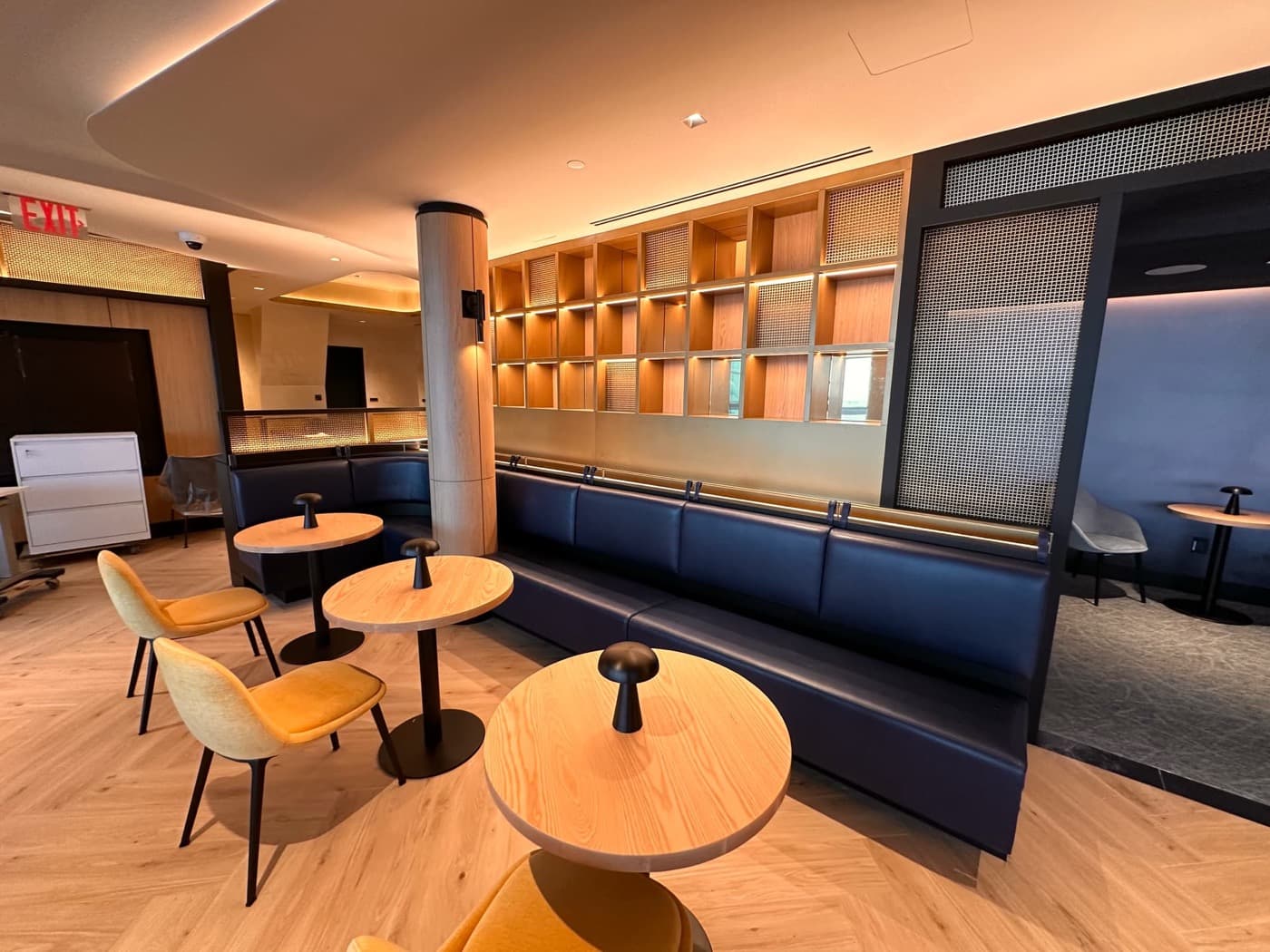 Lounge seating area with built-in dark upholstered banquette and illuminated timber display shelving