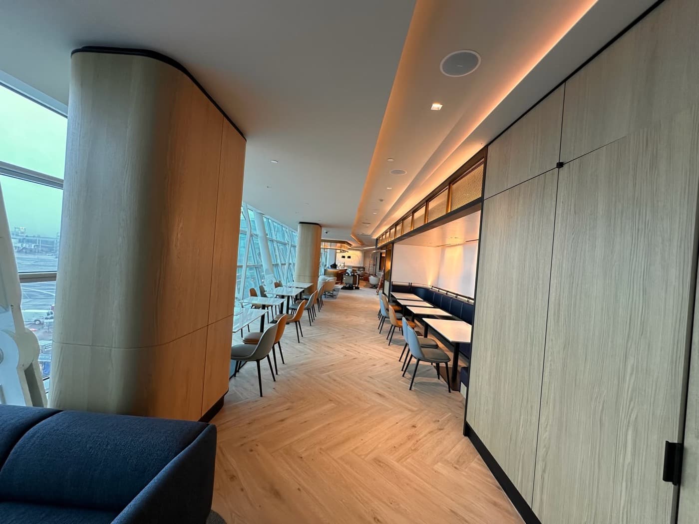 Lounge space featuring curved timber-clad columns, herringbone flooring, and built-in banquette booths