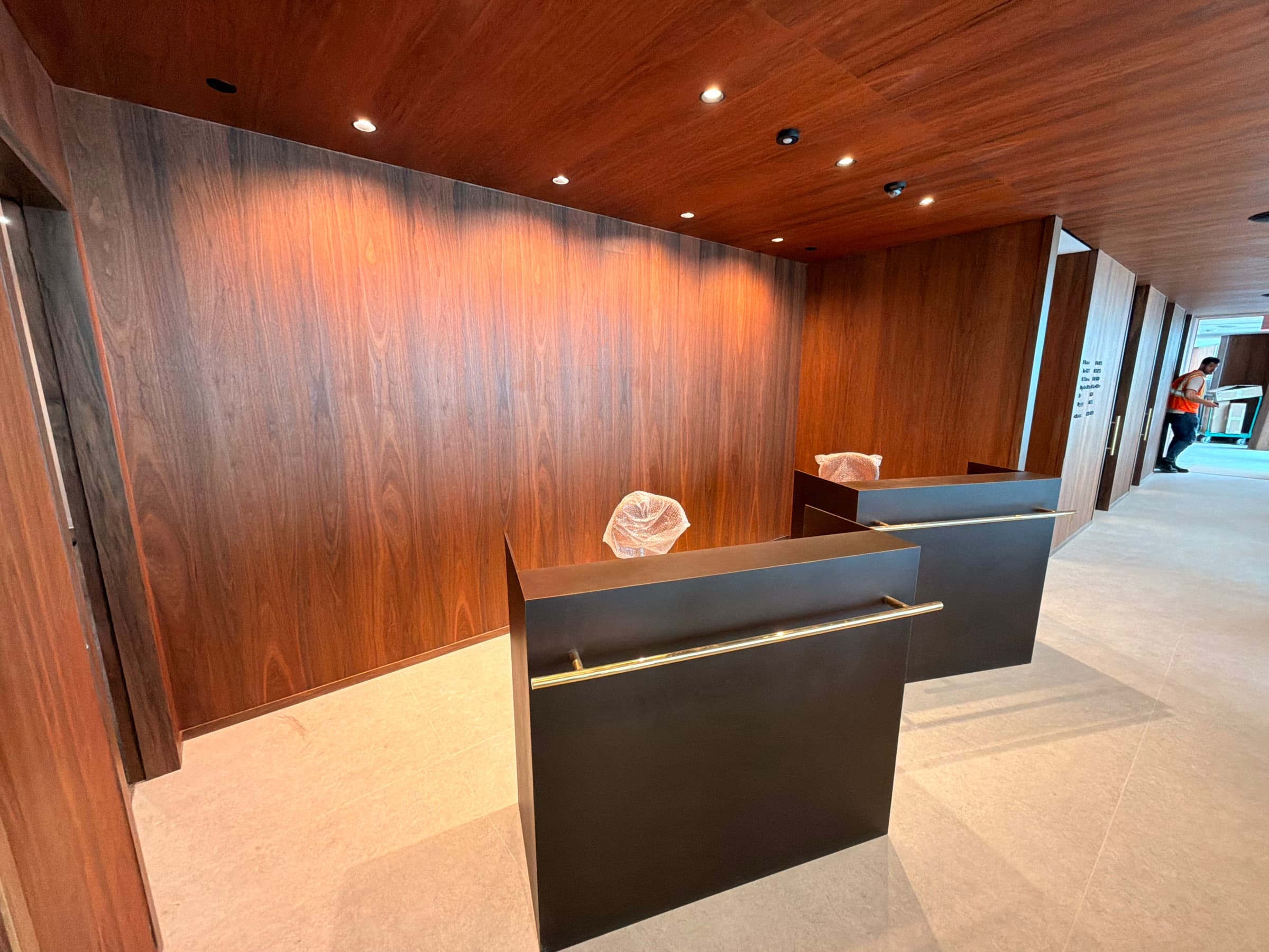 Commercial reception lobby with rich timber wall panelling and dark custom metal desks