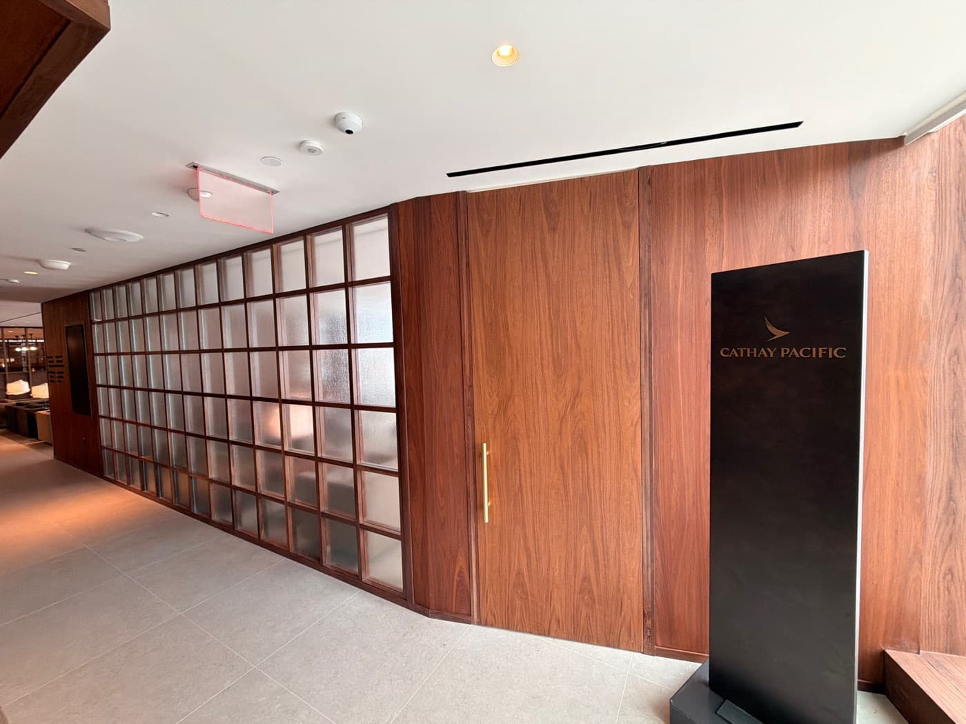 Lounge entrance corridor featuring warm timber wall panelling with integrated door and gridded glass partition