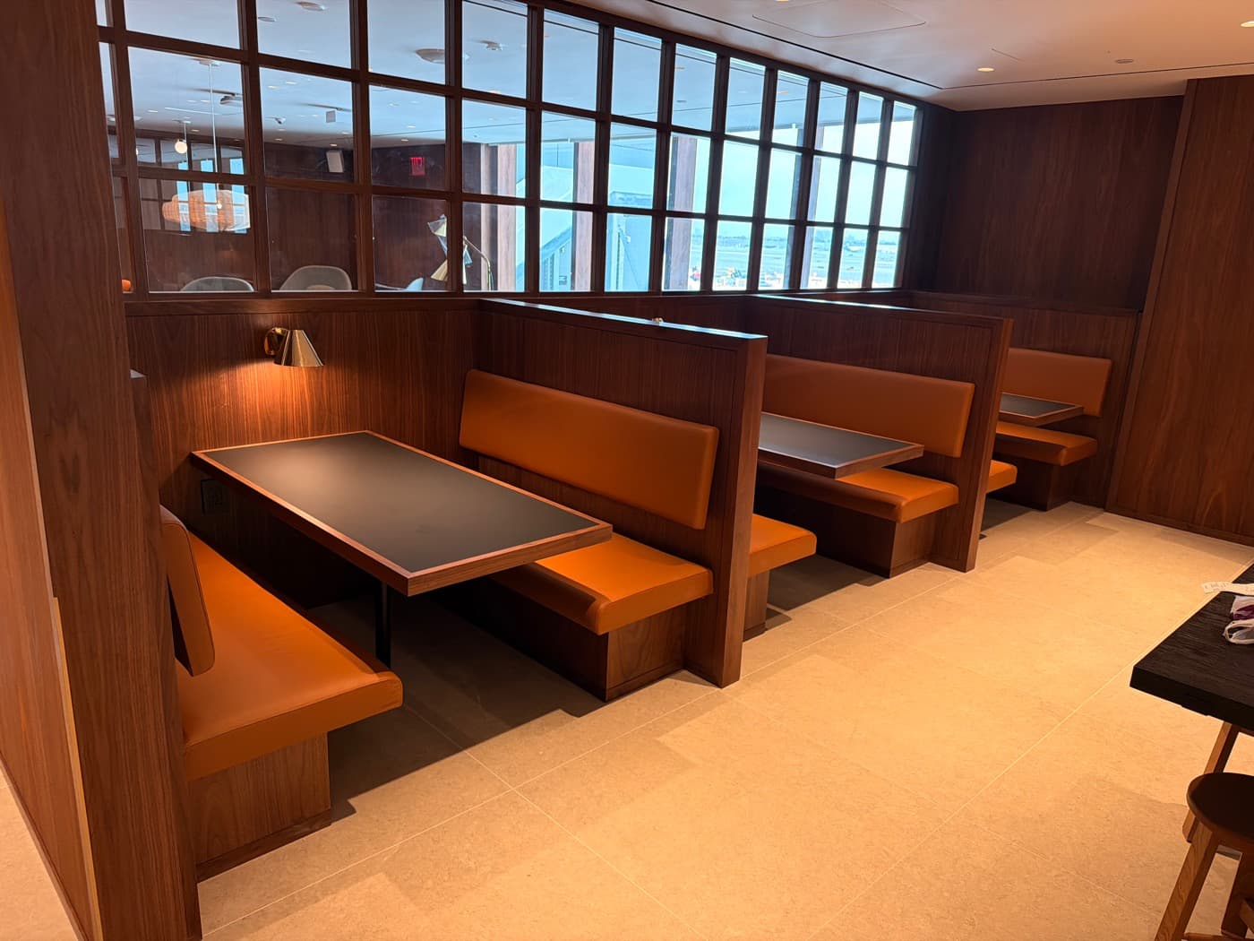 Dining area featuring custom timber booth seating, upholstered banquettes, and a gridded glass screen
