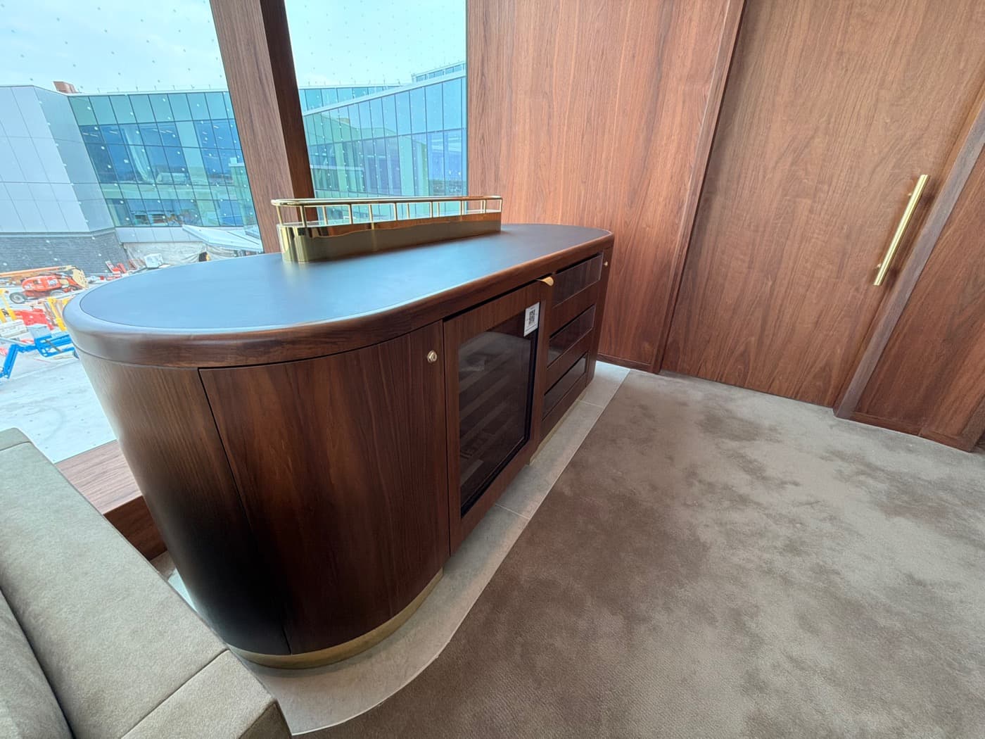 Lounge area with curved dark timber bar cabinet and matching timber wall panelling