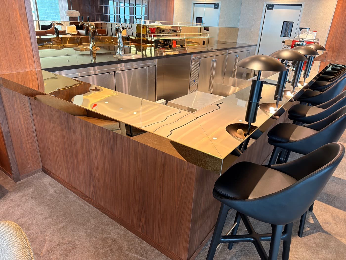 Lounge bar with rich timber panelling, polished brass-toned counter, and integrated task lighting fixtures