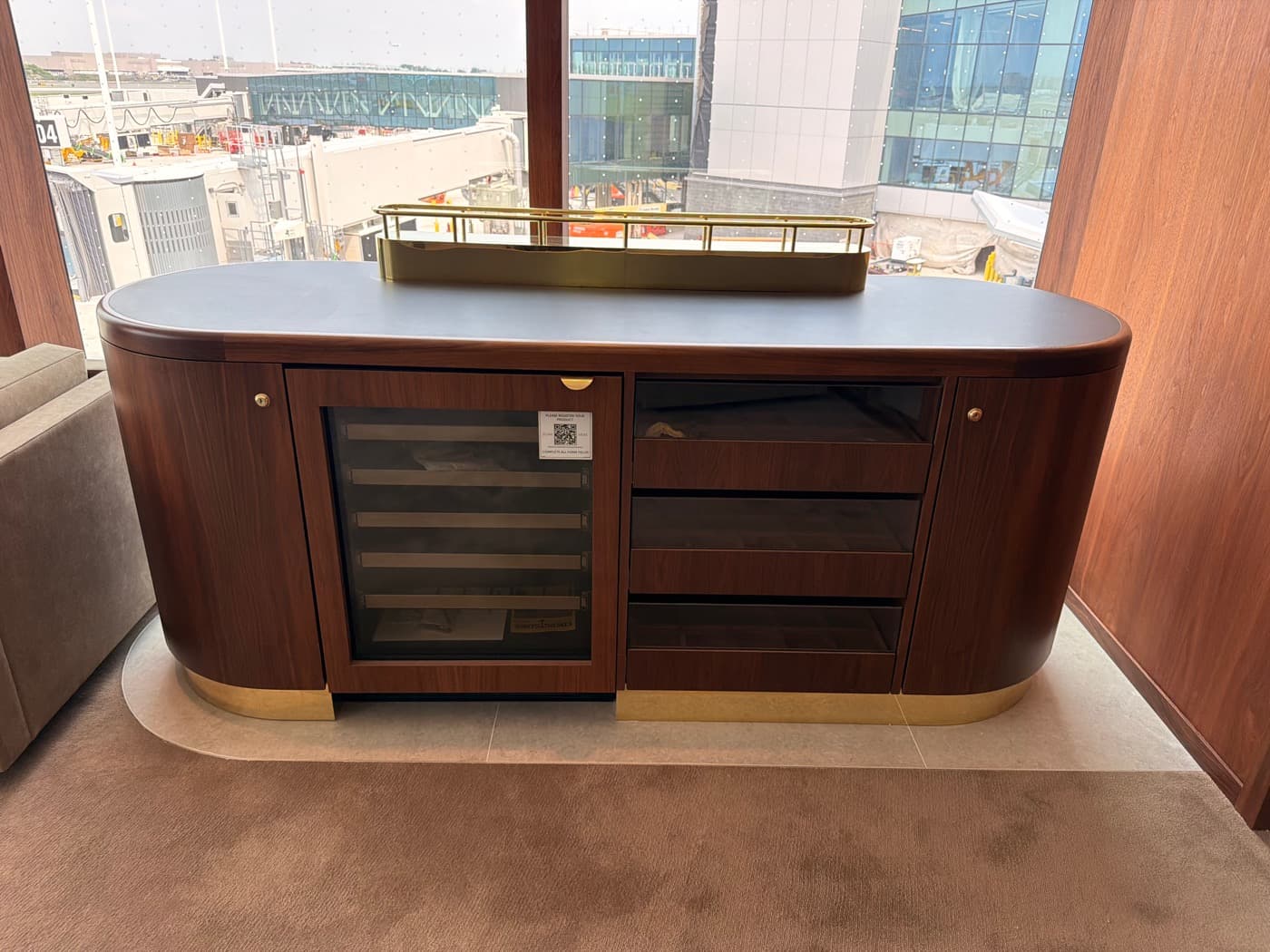 Lounge with custom curved timber credenza featuring an integrated wine cooler and brass detailing