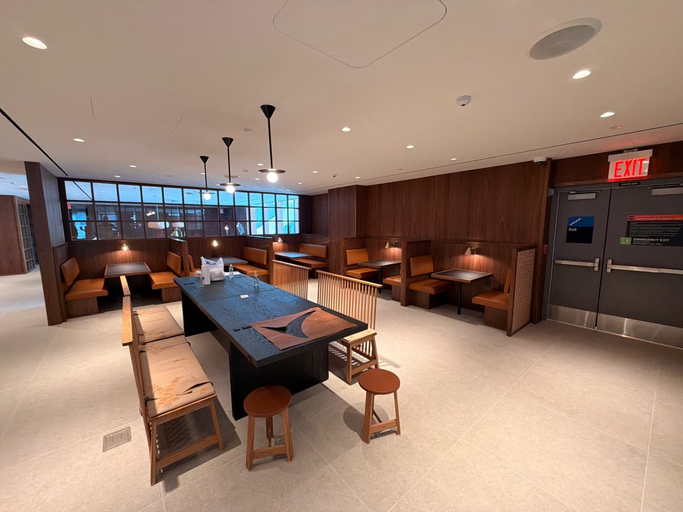 Dining lounge with warm timber wall panelling, built-in booths, and central communal table