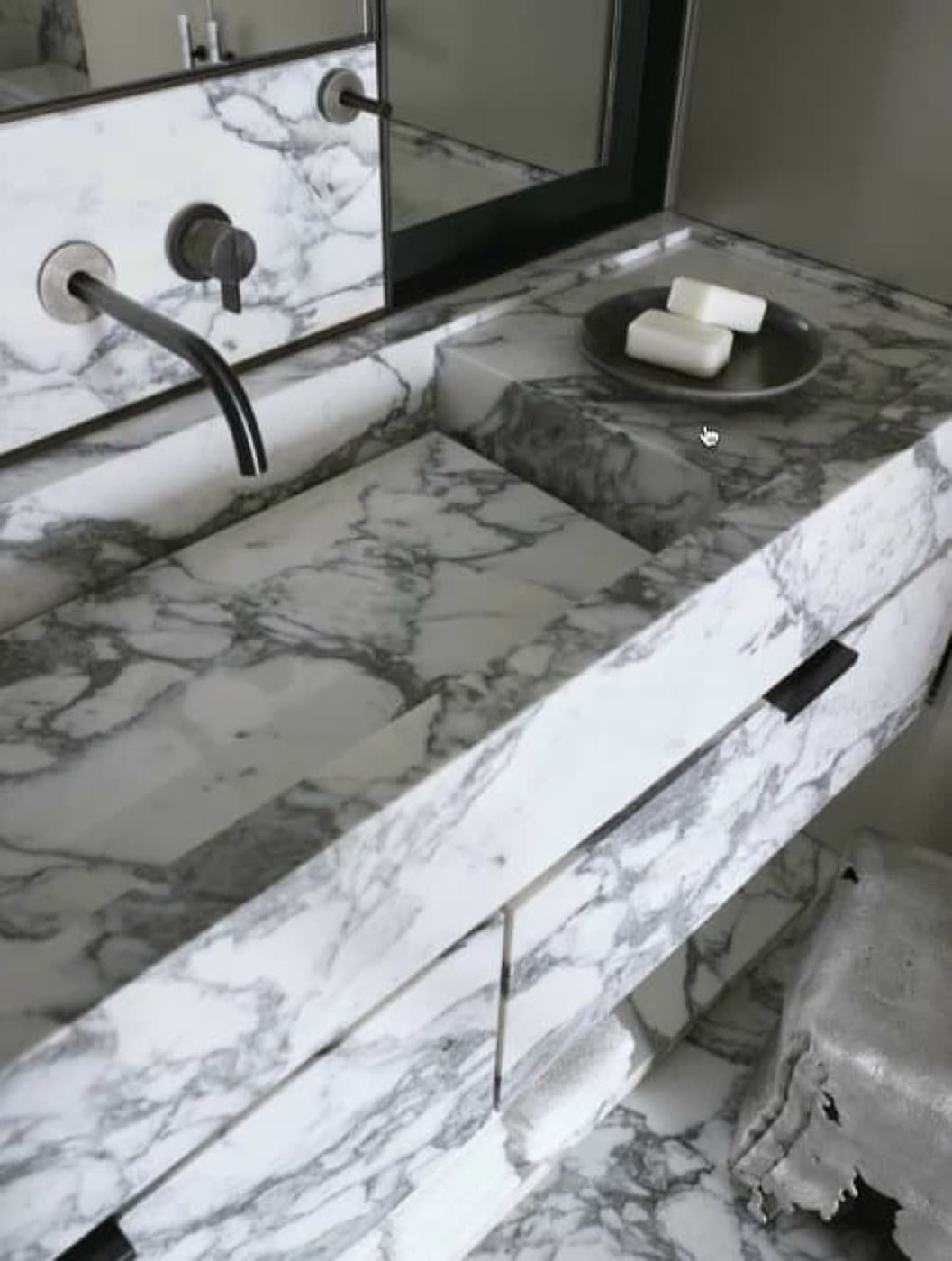 Bathroom featuring a pale veined stone vanity with integrated sink and dark wall-mounted fixtures