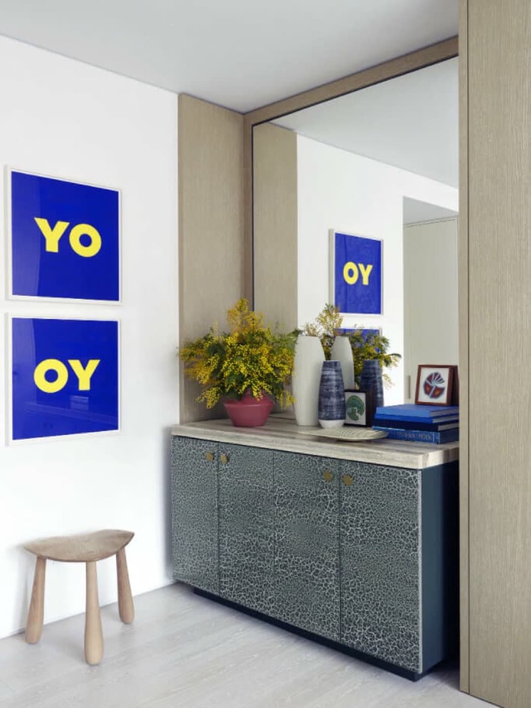 Entryway built-in alcove with light timber panelling, large mirror, and textured storage cabinet