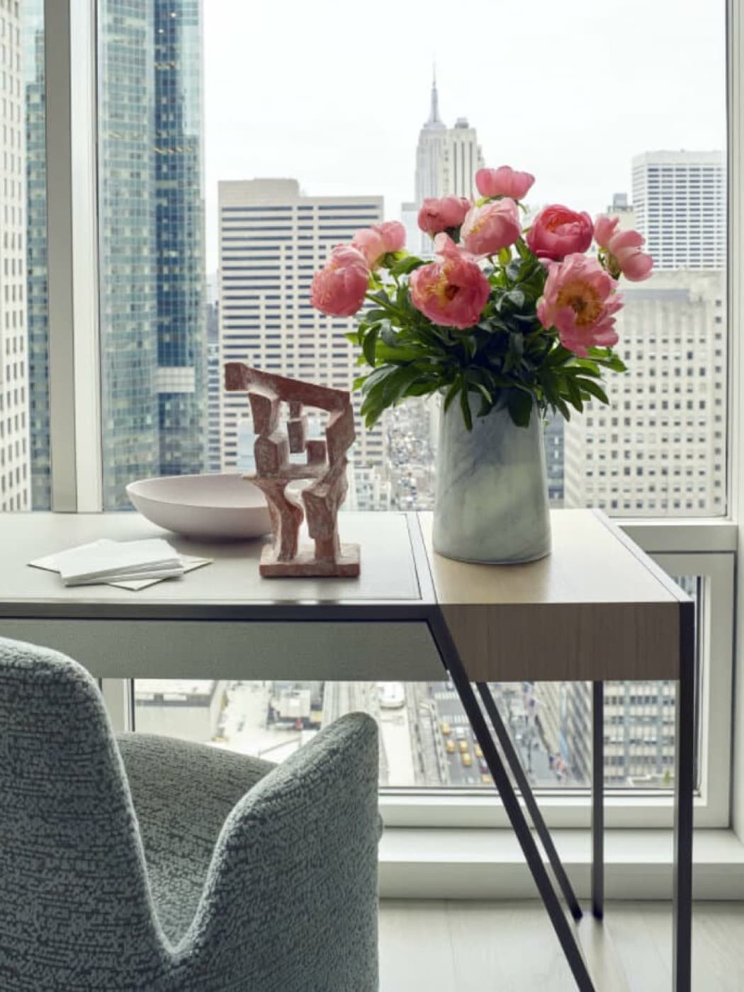 High-rise room with a pale timber desk and dark metal frame overlooking city skyline