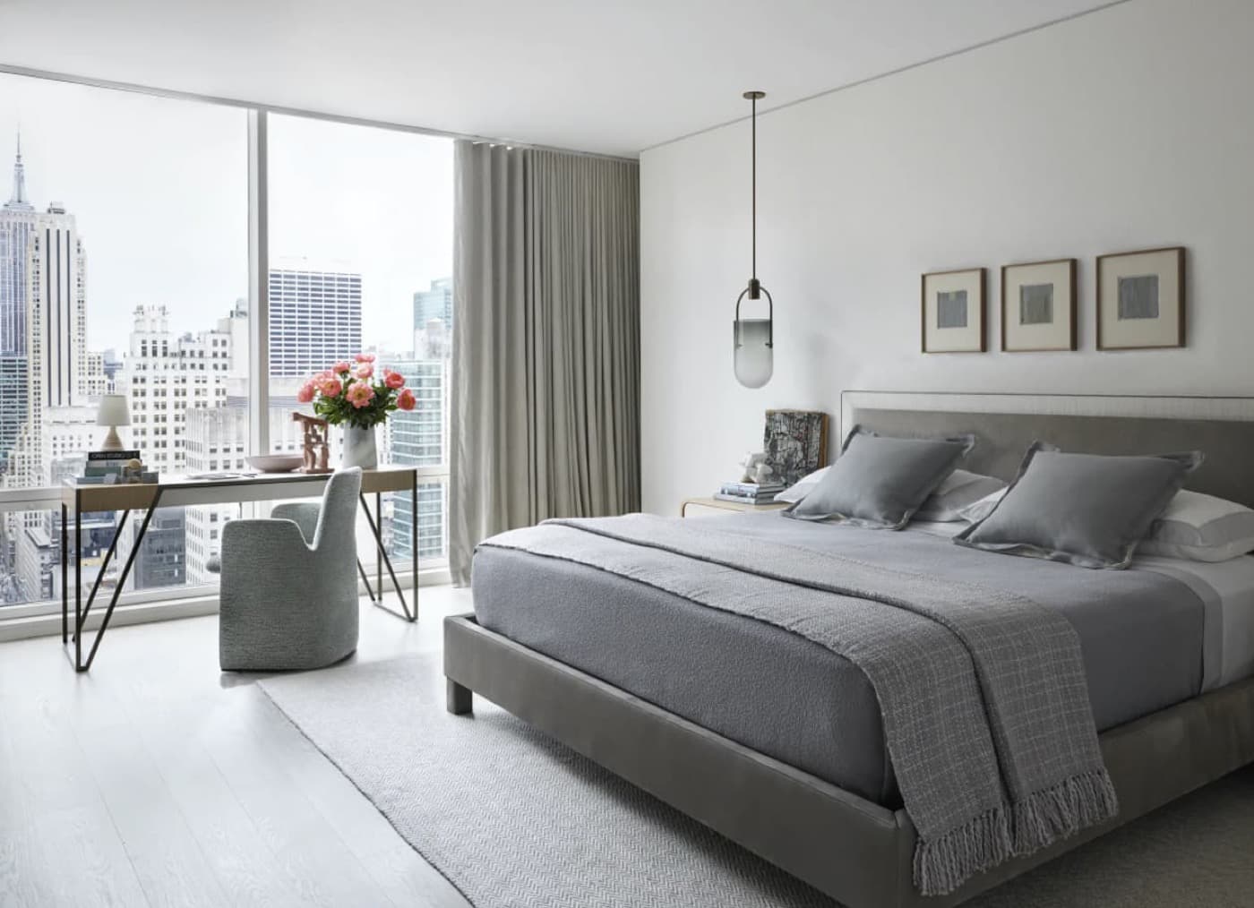 Modern bedroom with floor-to-ceiling windows overlooking the city skyline and an upholstered bed