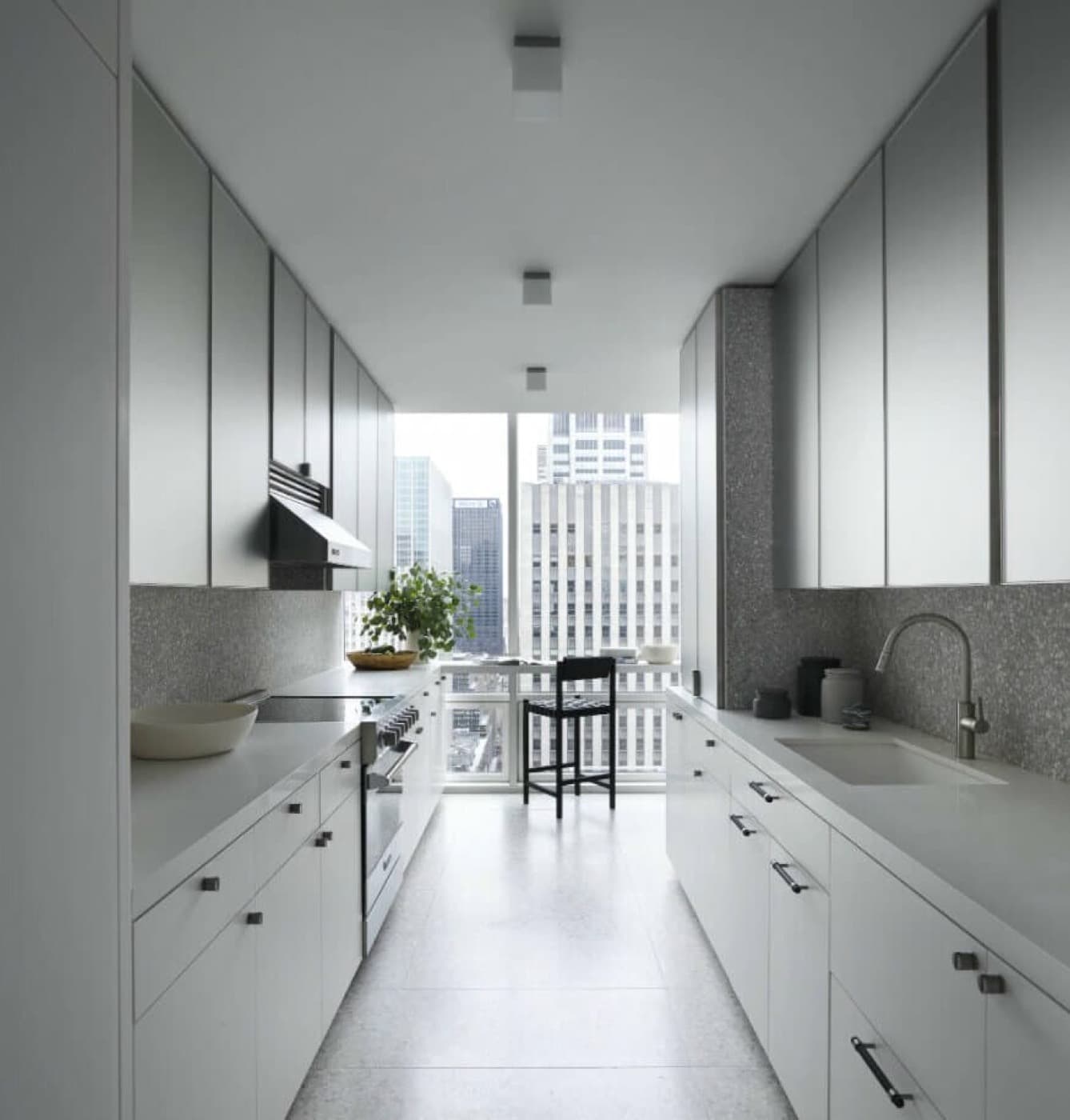 Galley kitchen with metallic upper cabinets, white lower cabinetry, and speckled stone backsplash