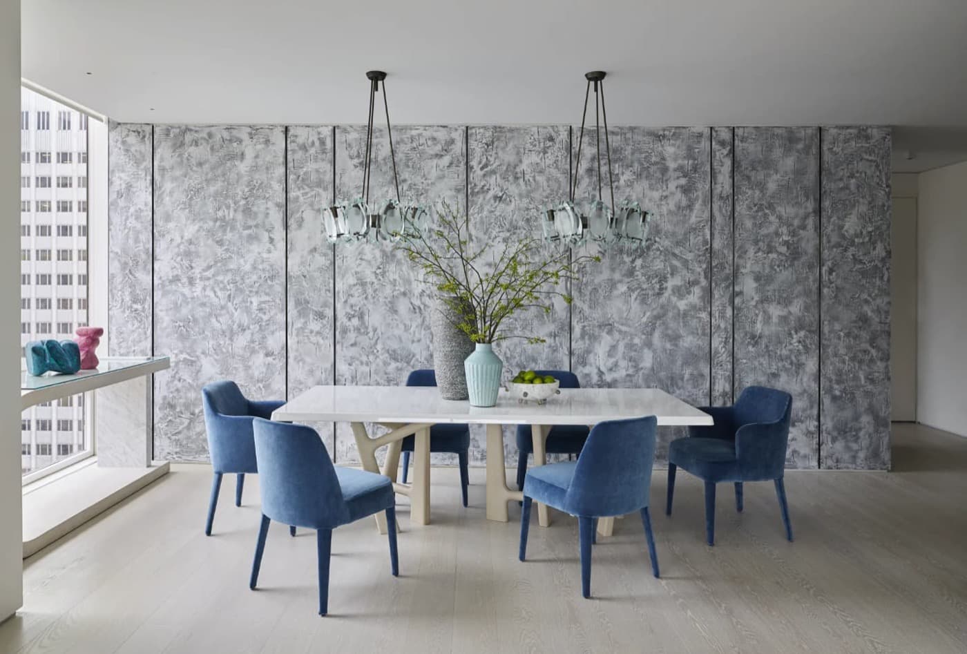 Dining area featuring textured wall panelling with vertical reveals and a pale dining table