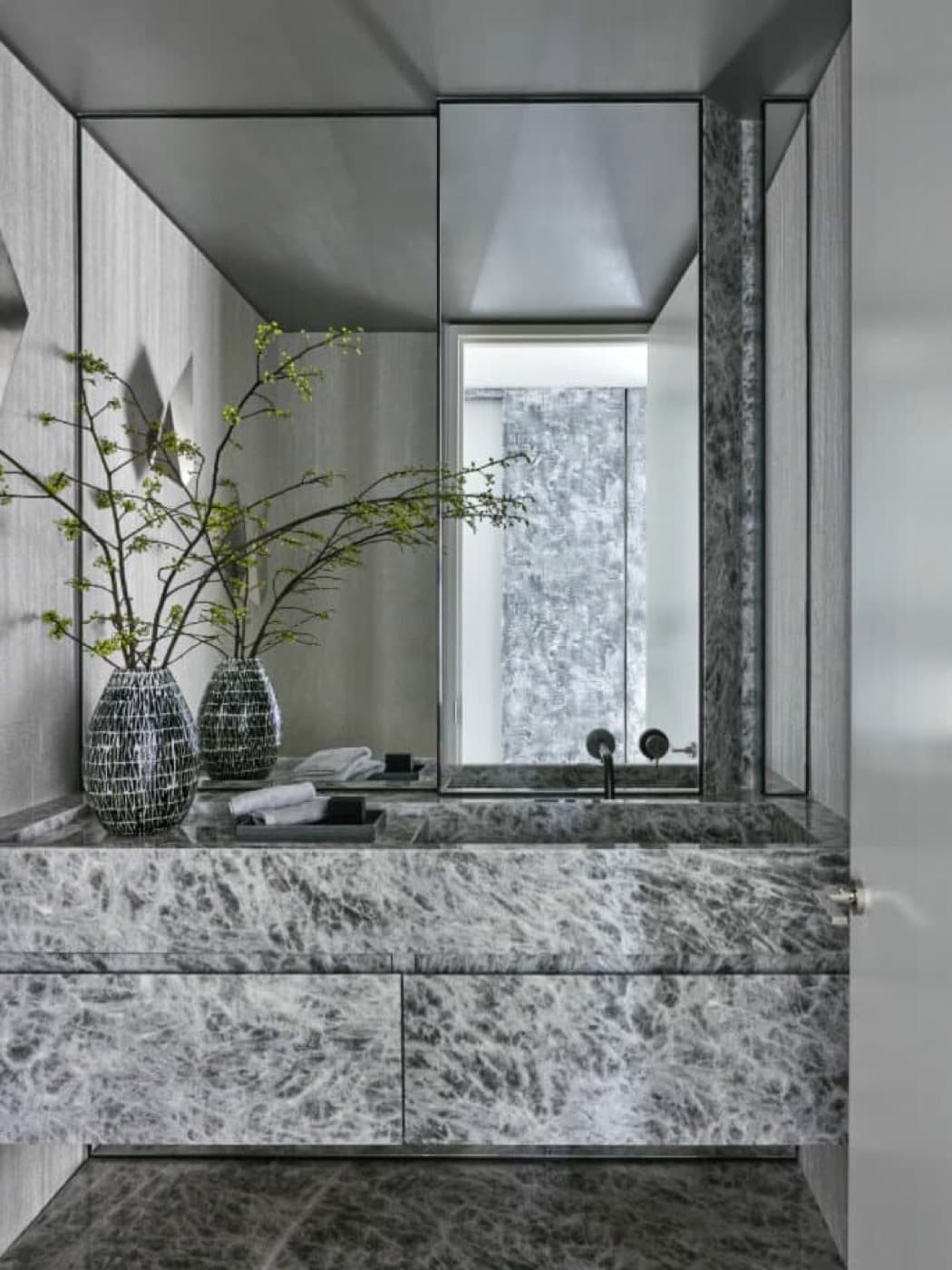 Powder room with a grey veined stone vanity, integrated sink and full-height mirror