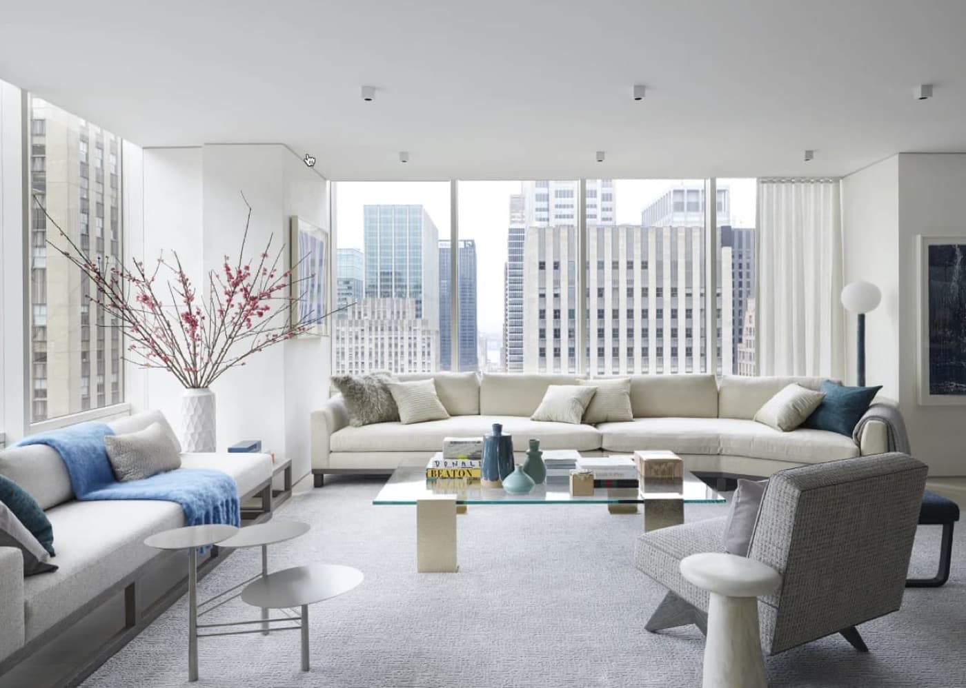 Contemporary living room with floor-to-ceiling windows overlooking city skyline and minimalist seating